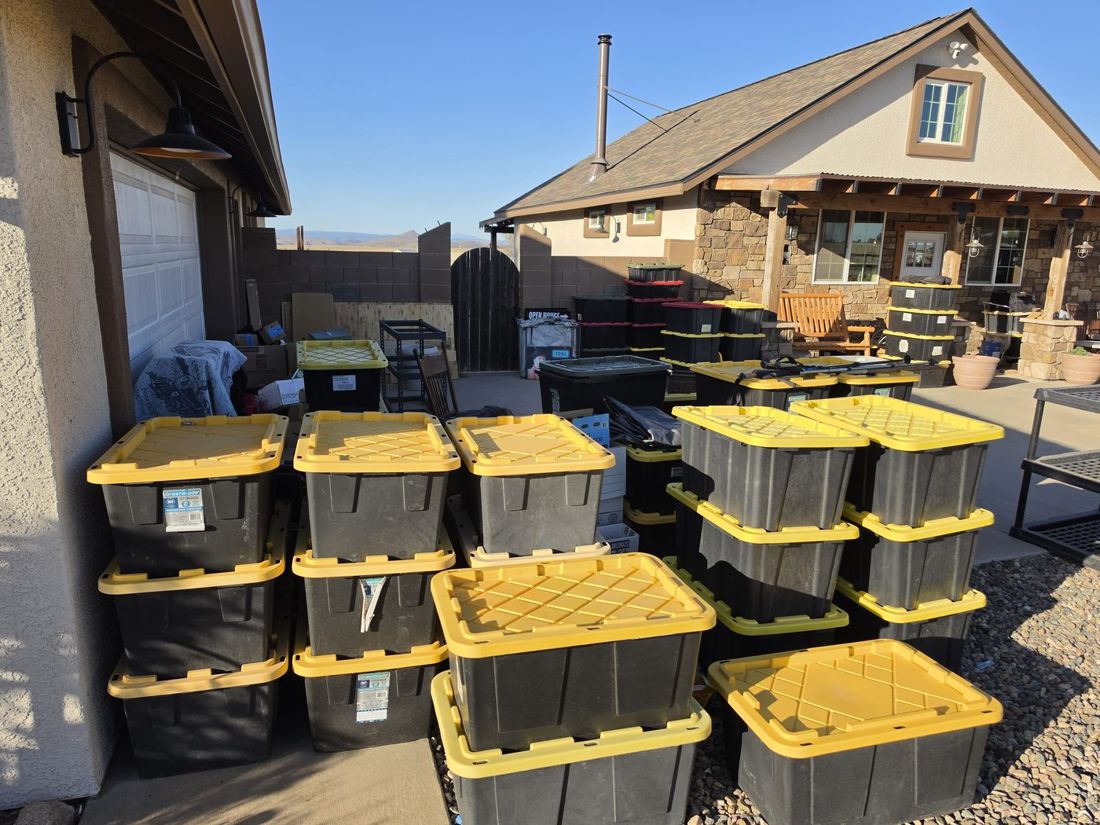 Approximately forty plastic storage bins of books staged in front of the BriteBound Books garage in Prescott, Arizona